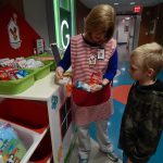 Volunteer Lisa Bolton tells a child about the available snacks on the Happy Wheels Cart.