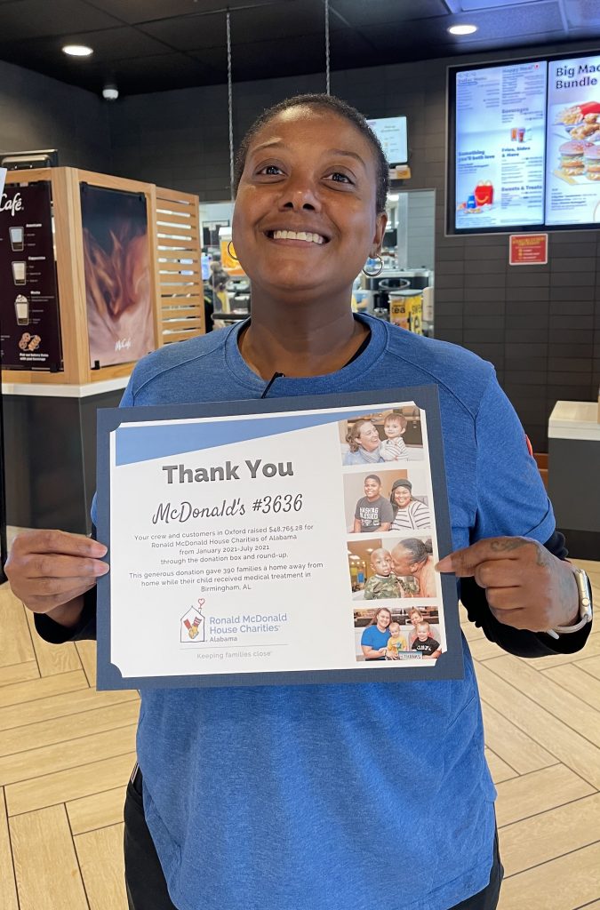 Woman holds up a certificate thanking her McDonald's crew for their fundraising efforts
